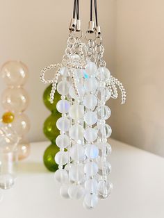 a glass beaded chandelier hanging from a hook on a table next to some vases