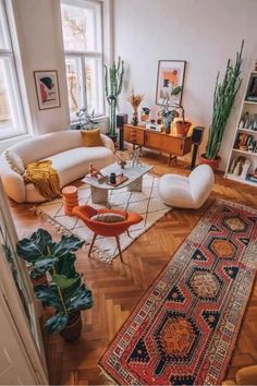 a living room filled with lots of furniture and plants on top of wooden flooring