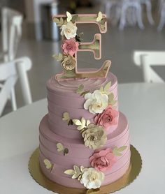 a three tiered cake decorated with flowers and the number five on top is pink