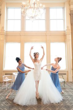 three bridesmaids in blue dresses are posing for the camera with their arms up