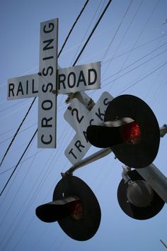 a railroad crossing sign hanging from the side of a traffic light