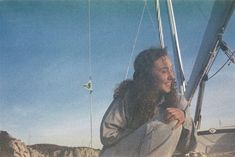 a man sitting on top of a sail boat in the ocean with long hair and beard