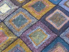 a multicolored crocheted blanket with squares on it