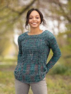 a woman standing in the grass with her hands on her hips and smiling at the camera