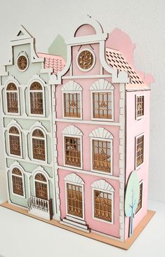 a paper model of a pink and white house on a wooden stand with a clock at the top