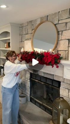 a woman standing in front of a fire place with flowers on the mantel and mantle