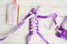 purple ribbon and other items on a white brick wall