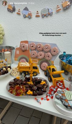 a table topped with lots of donuts covered in frosting next to other desserts