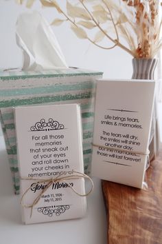 two folded cards sitting on top of a wooden table next to a vase with flowers