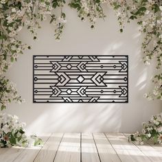 an art piece is hanging on the wall in front of some white flowers and greenery