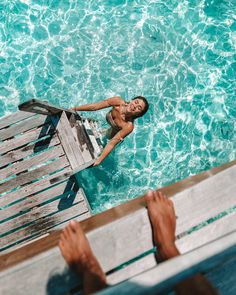 a man standing in the water next to a wooden dock with his feet up on it