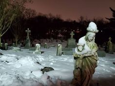 a statue in the middle of a snow covered cemetery