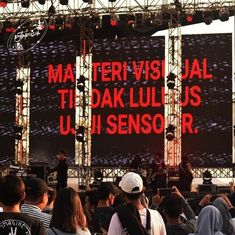 a group of people standing in front of a large screen with words on it that read ma tervis jal ti dak lu