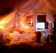 a dog sitting on top of a bed in a room with lights strung from the ceiling