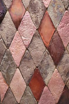 a close up view of a brick wall with different colored tiles on the outside and inside