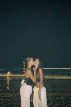 two women are kissing on the beach at night