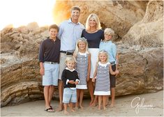 a family poses for a photo on the beach in front of some rocks and boulders