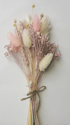 dried flowers are tied to a white wall