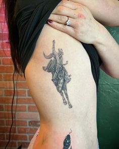 a woman with a tattoo on her back holding onto the side of her thigh and wearing a black shirt