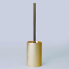 a gold toilet brush holder with a black handle on a gray background, in the shape of a cylinder