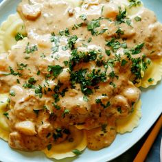 a white plate topped with meat covered in gravy next to utensils