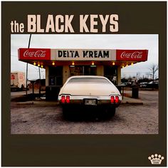 an old car is parked in front of the black keys