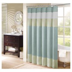 a bathroom with a tub, sink and shower curtain that has blue and green stripes on it