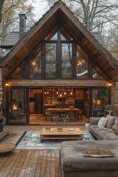 a living room with couches and tables in front of a wooden cabin style house