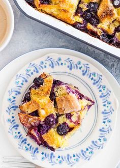 a blueberry cobbler on a plate next to a cup of coffee and a fork