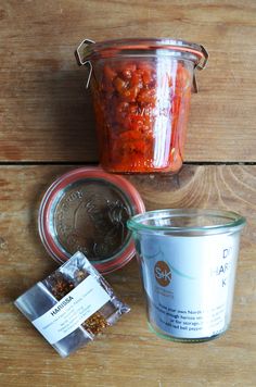 some food is sitting on a wooden table next to a jar and spoon with something in it