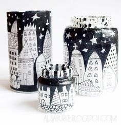 three black and white vases with buildings painted on the sides, one has a candle holder