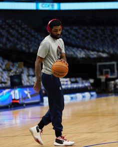 a man holding a basketball while standing on top of a basketball court in front of an arena