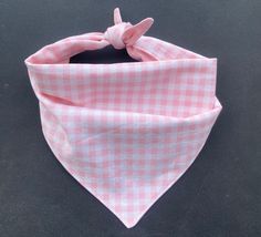 a pink and white checkered bandana with a knot on the top, sitting on a black surface