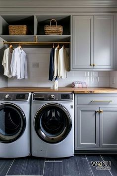 a washer and dryer in a small room with gray cupboards, white walls and wood flooring