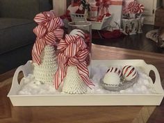 christmas decorations on a tray in the middle of a living room decorated with red and white ribbons