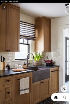 a kitchen with wooden cabinets and black counter tops, white tile flooring and a large window