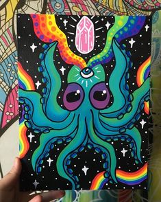 a person holding up a card with an octopus on it's face and rainbow colors