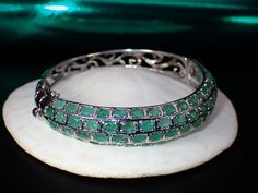 This fabulous little vintage treasure is a hinged natural emerald bangle bracelet that features 68 beautiful light green natural oval cut pave set emeralds. It measures approx. 6.75" inches in circumference, 2-1/4" inside opening and up to 1/2" wide. It weighs 22.76 grams. The bracelet is functioning and secure. Please bear in mind this is a previously owned and loved vintage treasure which shows signs of wear. Please inspect all photos prior to purchase. Items $100 or more are shipped in a high Exquisite Green Jewelry With Pave Setting, Luxury Oval Gemstone Bangle, Oval Emerald Bracelets For Anniversary, Luxury Green Oval Bracelet, Oval Gemstone Bangle For Formal Events, Fine Jewelry Green Oval Bracelets, Green Oval Bracelets Fine Jewelry, Oval Green Bracelets Fine Jewelry, Oval Gemstone Bangle In Fine Jewelry Style