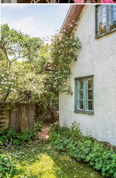 an old house with flowers growing on the outside and in the inside, next to a garden