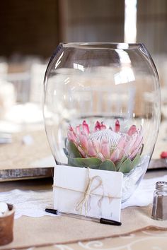 a vase with flowers in it sitting on a table next to candles and napkins