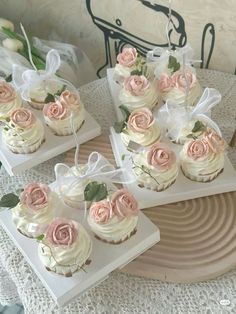 cupcakes with white frosting and pink roses on them are sitting on plates