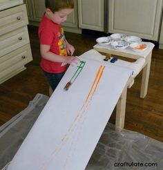 a young boy is painting on an easel in the kitchen with his crayons