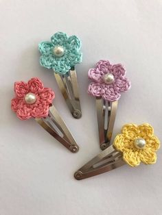 four crocheted flower hair clips with pearls on each side and one pearl in the middle