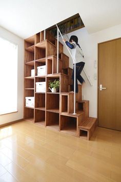 a person climbing up the stairs in a room with wooden floors and shelving units