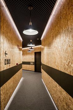 an empty hallway with wood paneling and black trim on the walls is lit by recessed lights