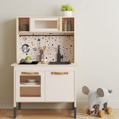 a wooden toy kitchen with an elephant figurine next to it