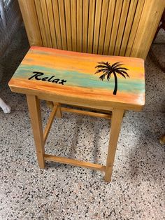 a wooden stool with a palm tree painted on the side and relax written on it