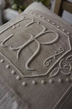 a close up of a pillow on a chair with embroidered letters and dots around the edges