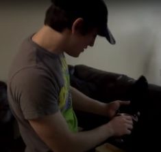 a young man sitting on top of a couch next to a black cat