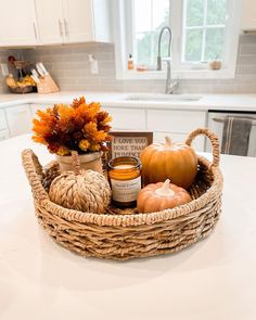 a wicker basket filled with pumpkins and spices on a white counter top in a kitchen